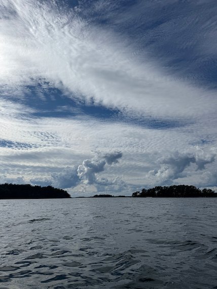 Low islands under streaky white clouds, seen from a kayak
