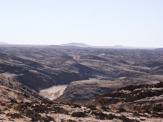 A deep canyon cuts through dark rock under a hazy sky in southern Namibia.