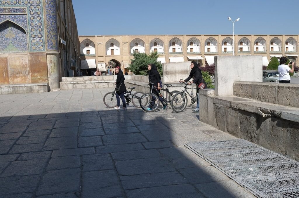 People with bicycles on Naqsh-e Jahan Square by the Shah Mosque