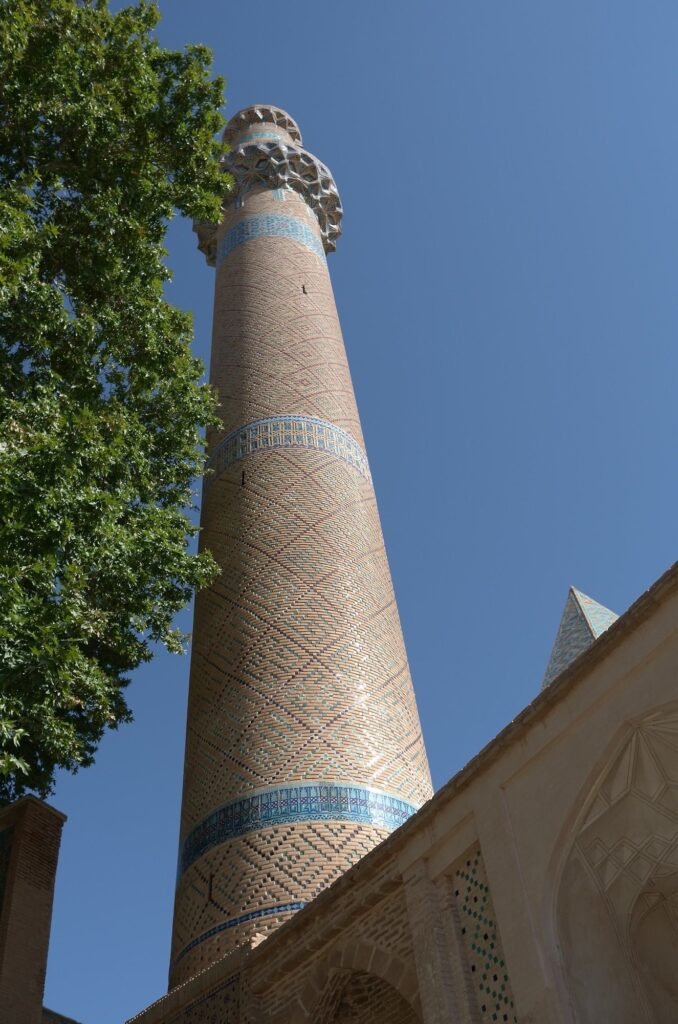 Tall brick minaret of the Jameh Mosque of Natanz under a blue sky