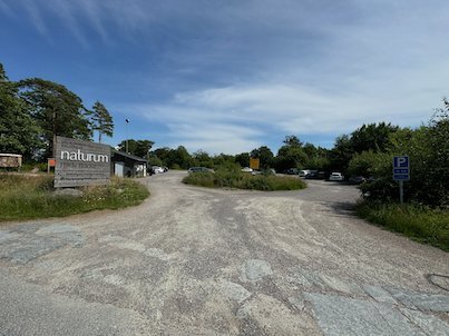 Entrance road and parking at Naturum Fjärås, with the naturum sign and pine trees