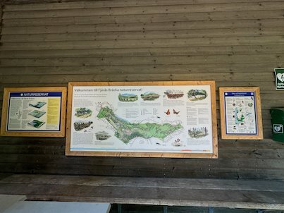 Map boards of the Fjärås Bräcka nature reserve on a wooden wall at Naturum Fjärås