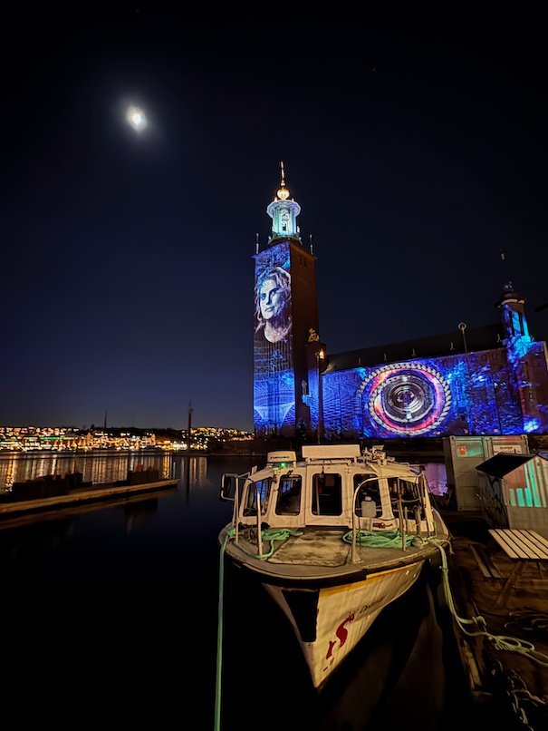 Blue circle pattern on the facade and a portrait on the tower of Stockholm City Hall at night