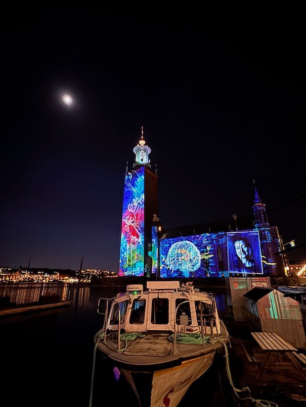 Projection of a human brain and a portrait on the facade of Stockholm City Hall at night