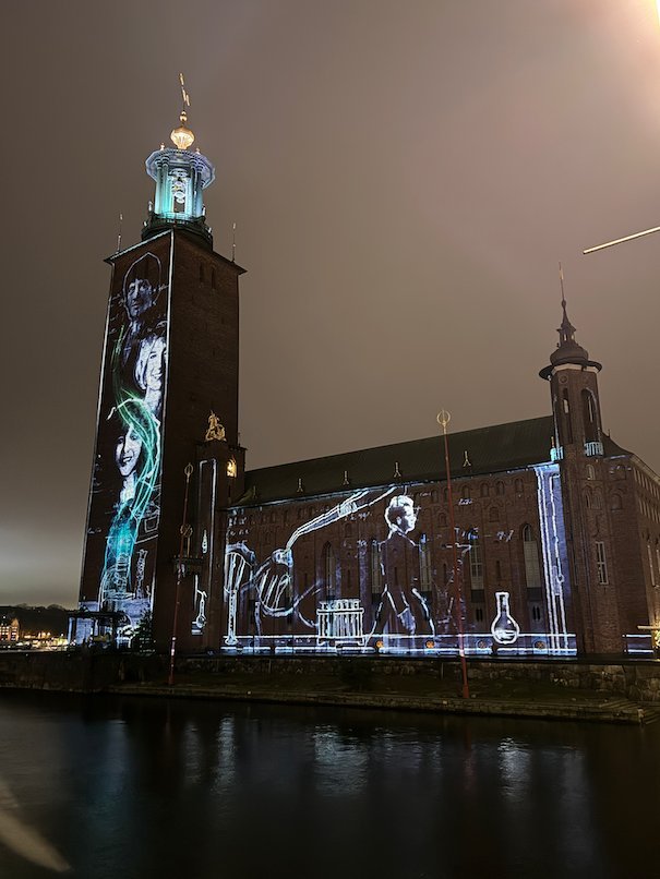 Line drawing of a woman working in a laboratory, projected on the facade of Stockholm City Hall