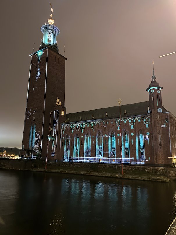 Stockholm City Hall on a cloudy night with cyan light patterns along the facade