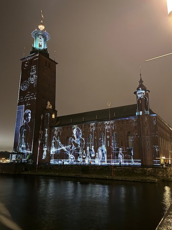 Projected drawings of scientists and laboratory flasks on the facade of Stockholm City Hall