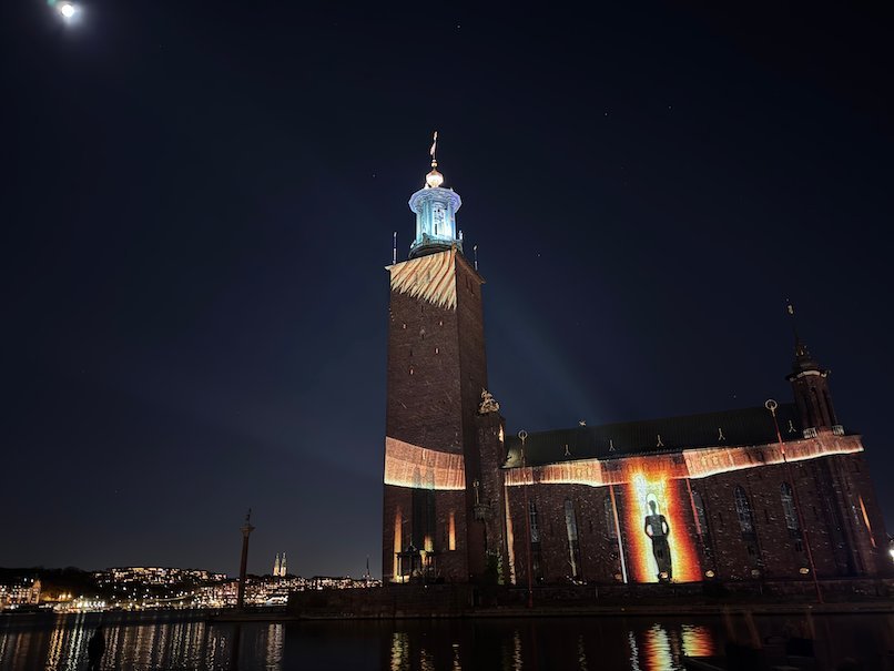 Stockholm City Hall at night with a projected figure in a doorway of light on the facade