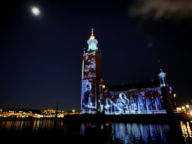 Stockholm City Hall with white and blue projections, reflected in the water under the moon
