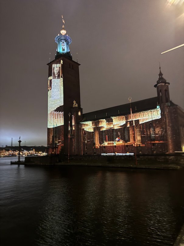 Stockholm City Hall with white light on the tower and facade, seen across the dark water
