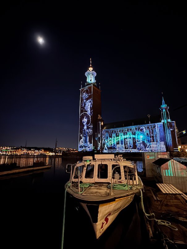 White line drawings projected on the tower and facade of Stockholm City Hall at night