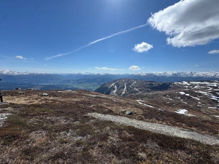Open mountain plateau above the tree line in Western Norway, with snow patches and a blue sky