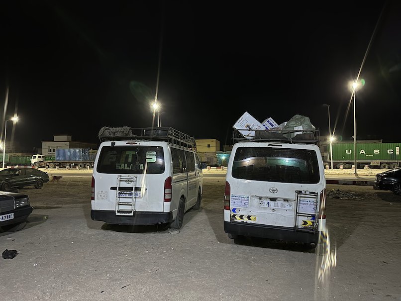 White minibuses with luggage racks park at night.
