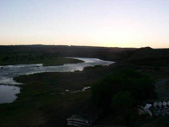 The Orange River winds through a dark valley at dusk on the border of South Africa and Namibia.