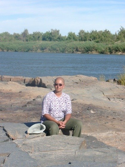 Zayera Khan sits on flat rocks beside the wide Orange River on the South Africa and Namibia border.