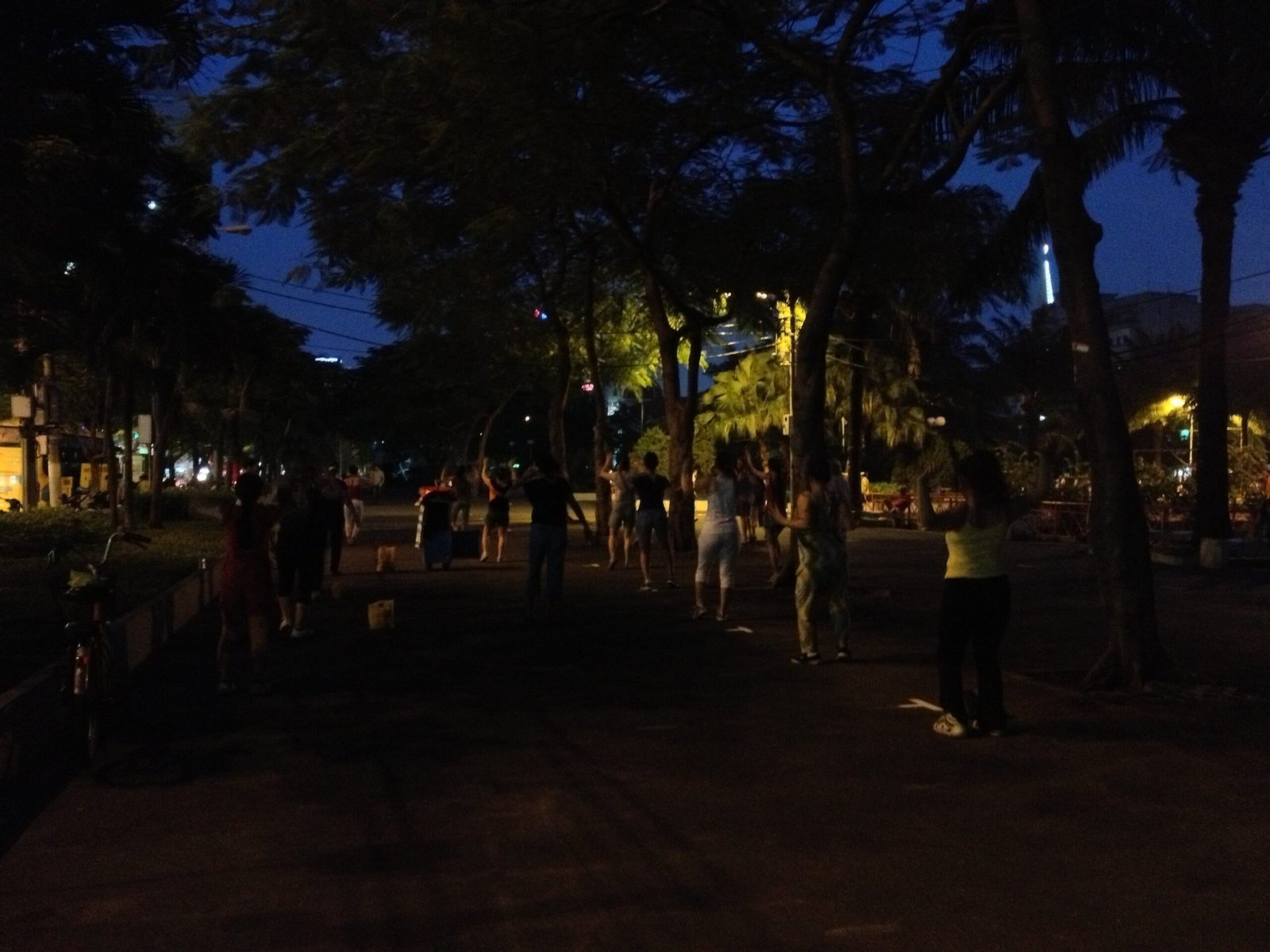 People exercise together in a dark park in Phnom Penh in the evening.