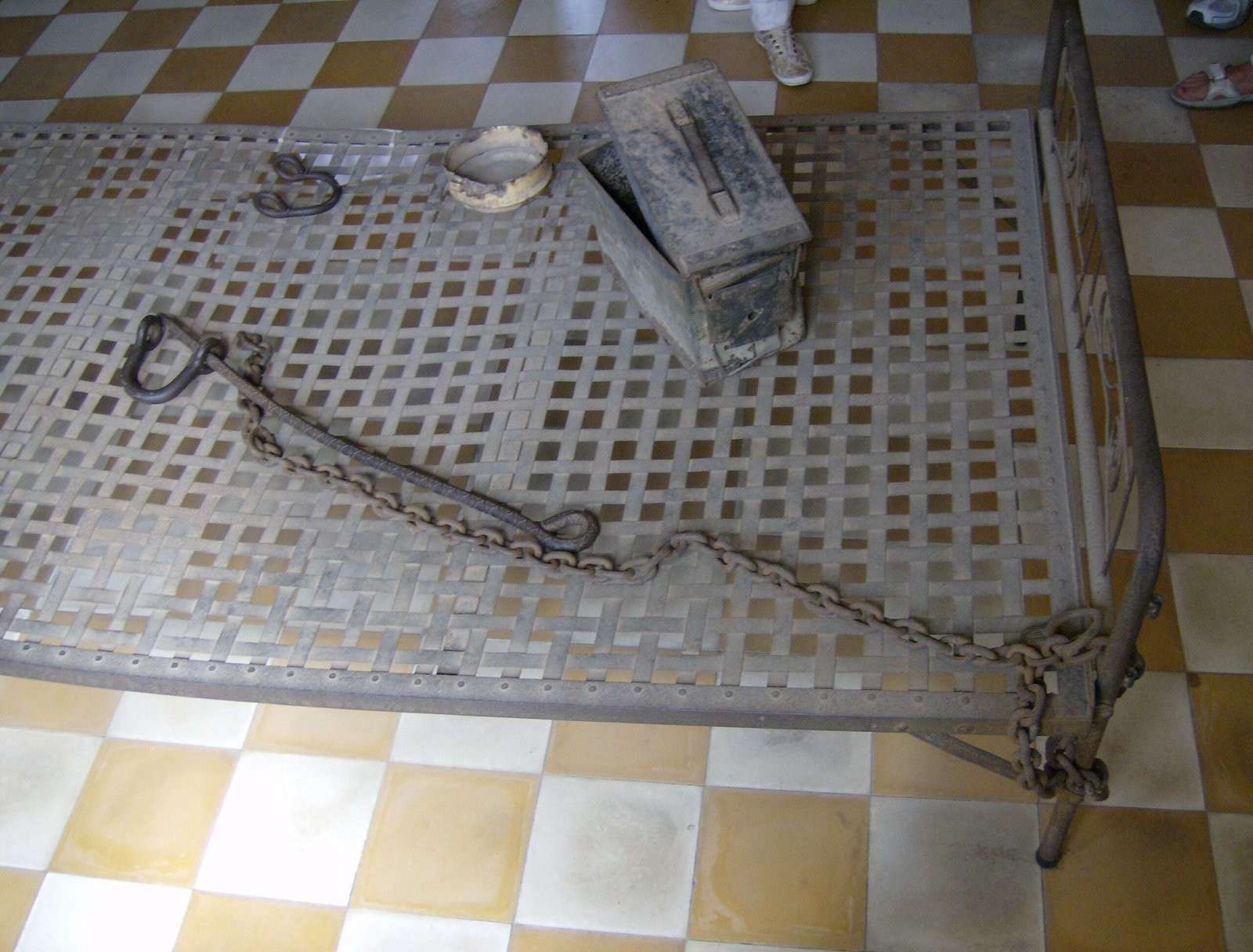 A metal bed with chains and an ammunition box stands at Tuol Sleng in Phnom Penh.