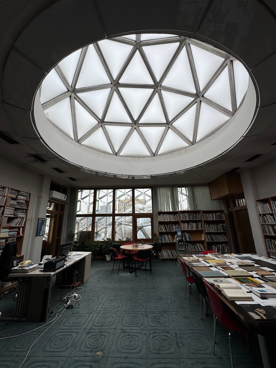 A round glass dome lights a reading room with bookshelves and tables in the National Library in Pristina.