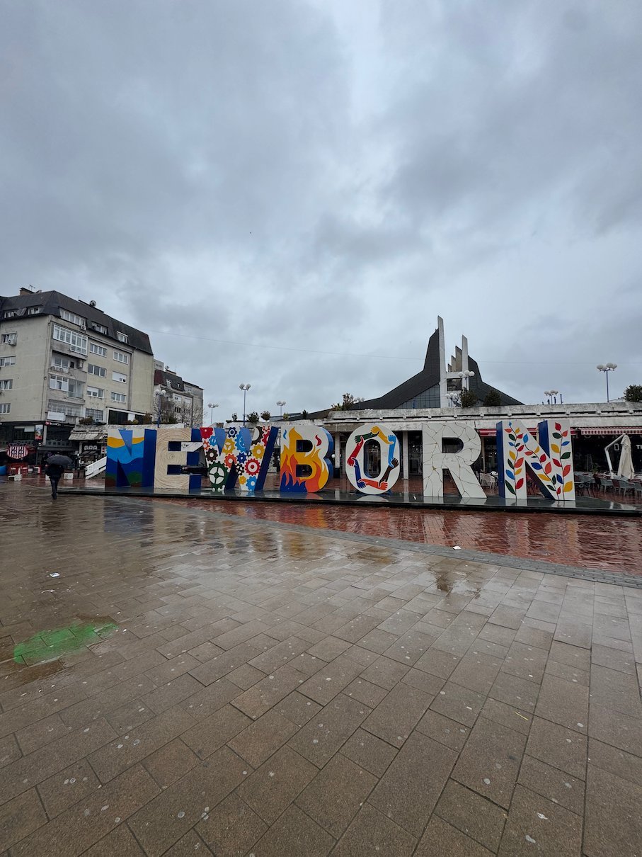 The colourful NEWBORN letters stand on a wet pedestrian square in central Pristina.