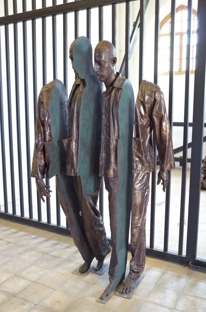 Two bronze figures in front of iron bars at the Qasr Prison Museum