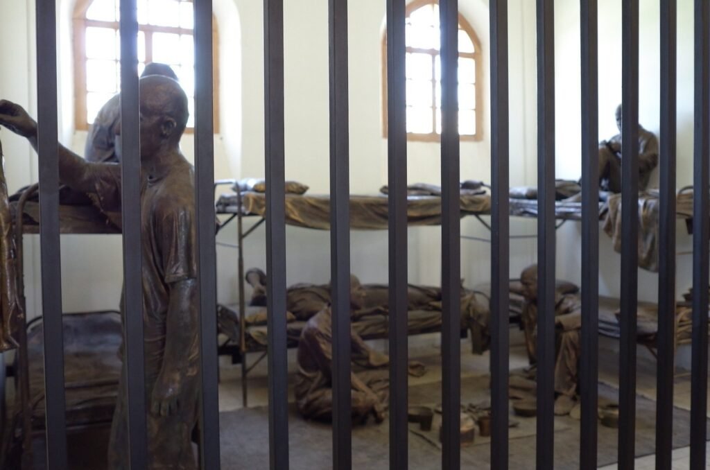Bronze figures of prisoners behind iron bars at the Qasr Prison Museum