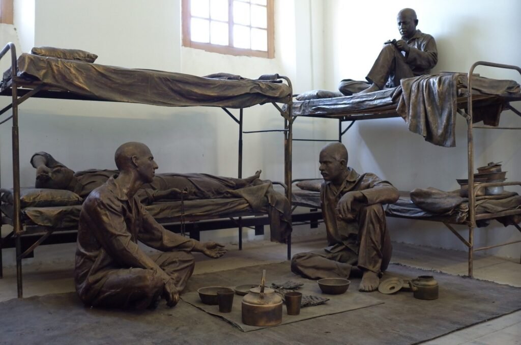 Bronze figures of prisoners who eat and rest on bunk beds in a cell
