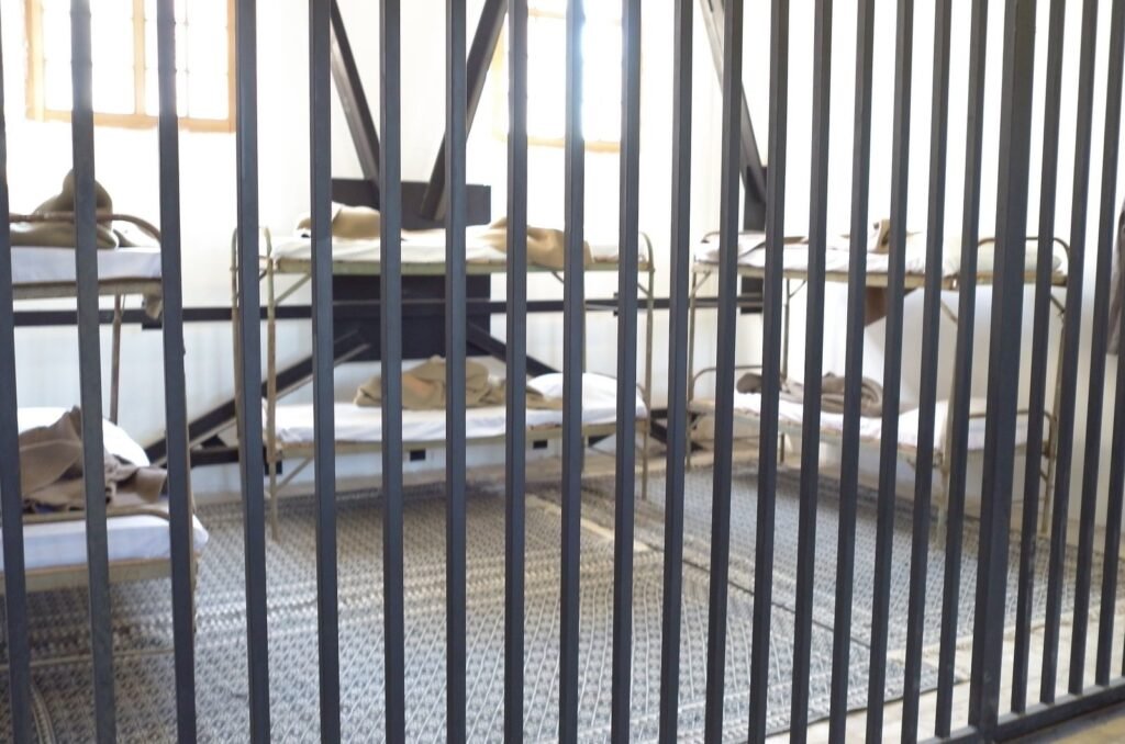 Prison cell with bunk beds behind iron bars at the Qasr Prison Museum
