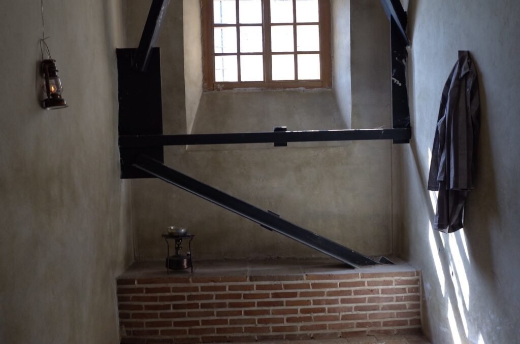 Prison cell with a small window, an iron frame and an old lamp