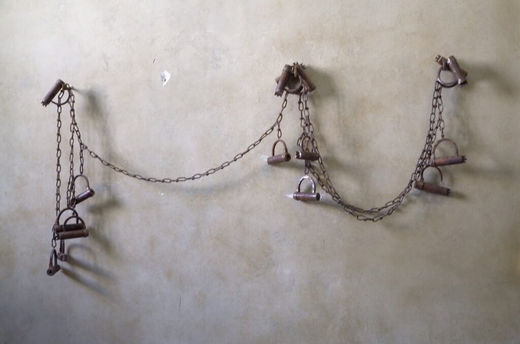 Old iron chains and shackles on a wall at the Qasr Prison Museum