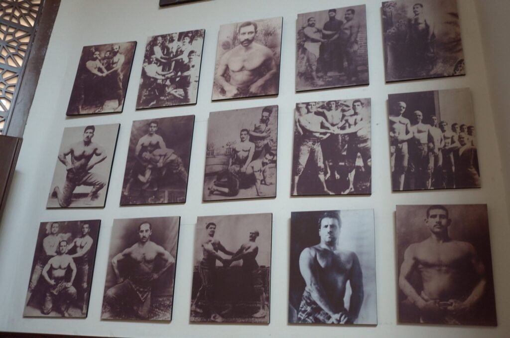 Old photos of wrestlers and strong men on a wall at the Qasr Prison Museum
