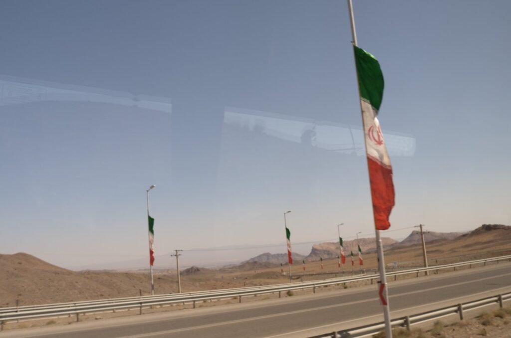 Iranian flags along a highway in the desert, seen from the bus