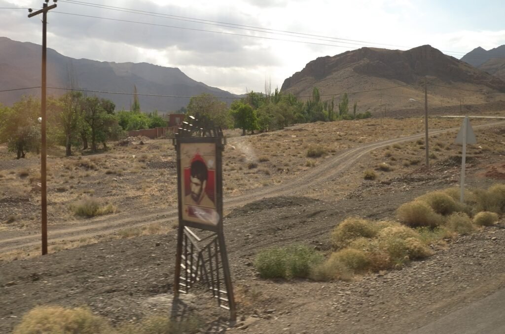 Dry hills, trees and a roadside sign on the way to Abyaneh