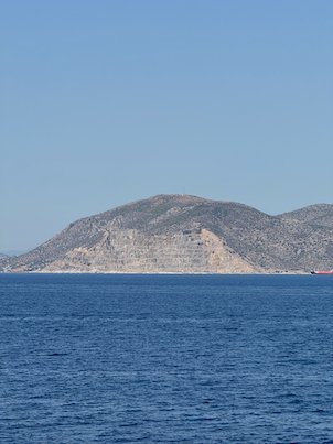 Steep rocky island hill rising from the blue sea in the Saronic Gulf