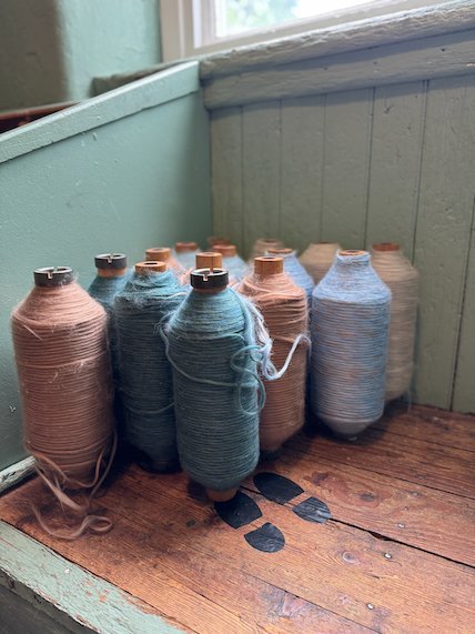 Pink and blue yarn bobbins on a wooden window sill