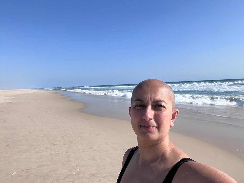 Zayera Khan takes a selfie on a wide beach with waves near Saint-Louis.