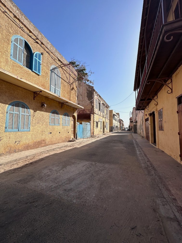 A quiet street with colonial houses and blue shutters in Saint-Louis.