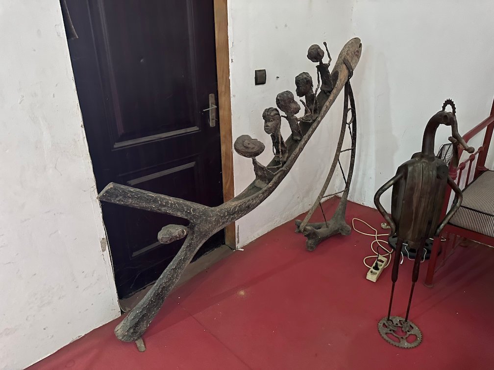 Metal sculptures of figures stand in the corner of a gallery.