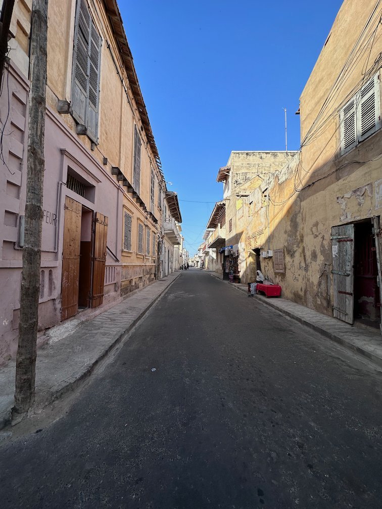 A long straight street runs between old houses in Saint-Louis.