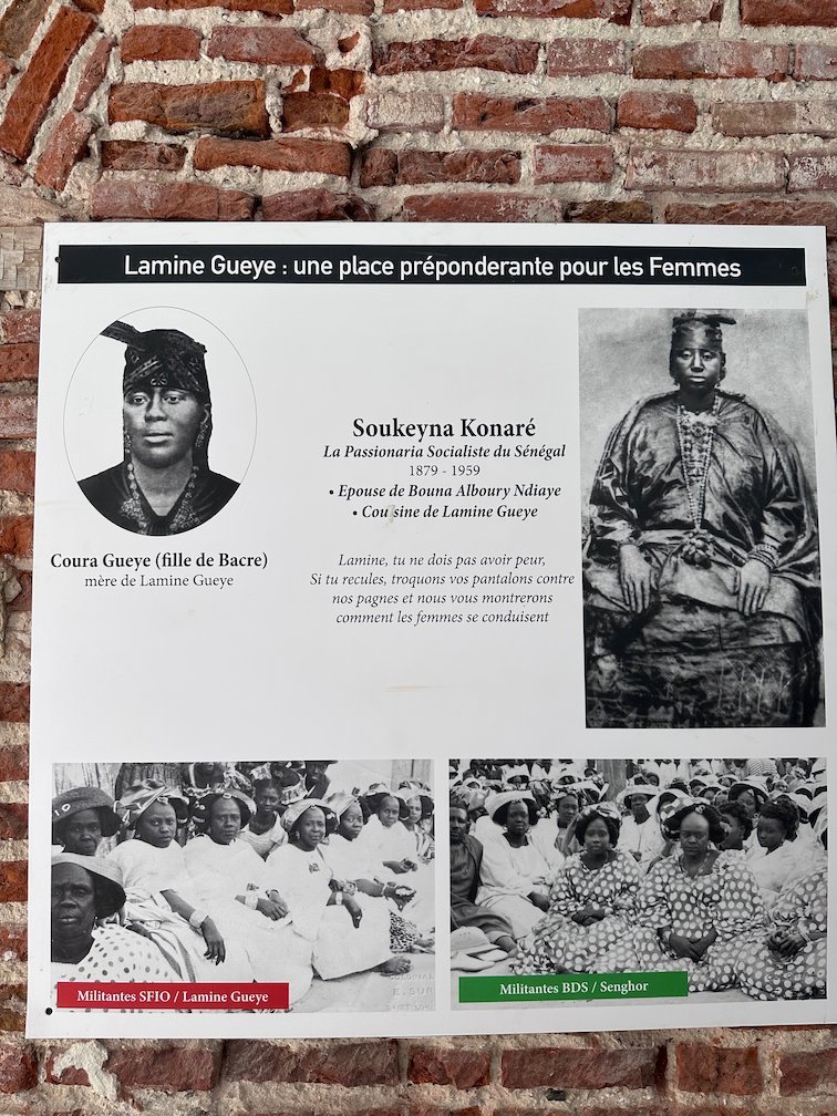 A museum panel about Lamine Gueye and women in Senegal hangs on a brick wall.