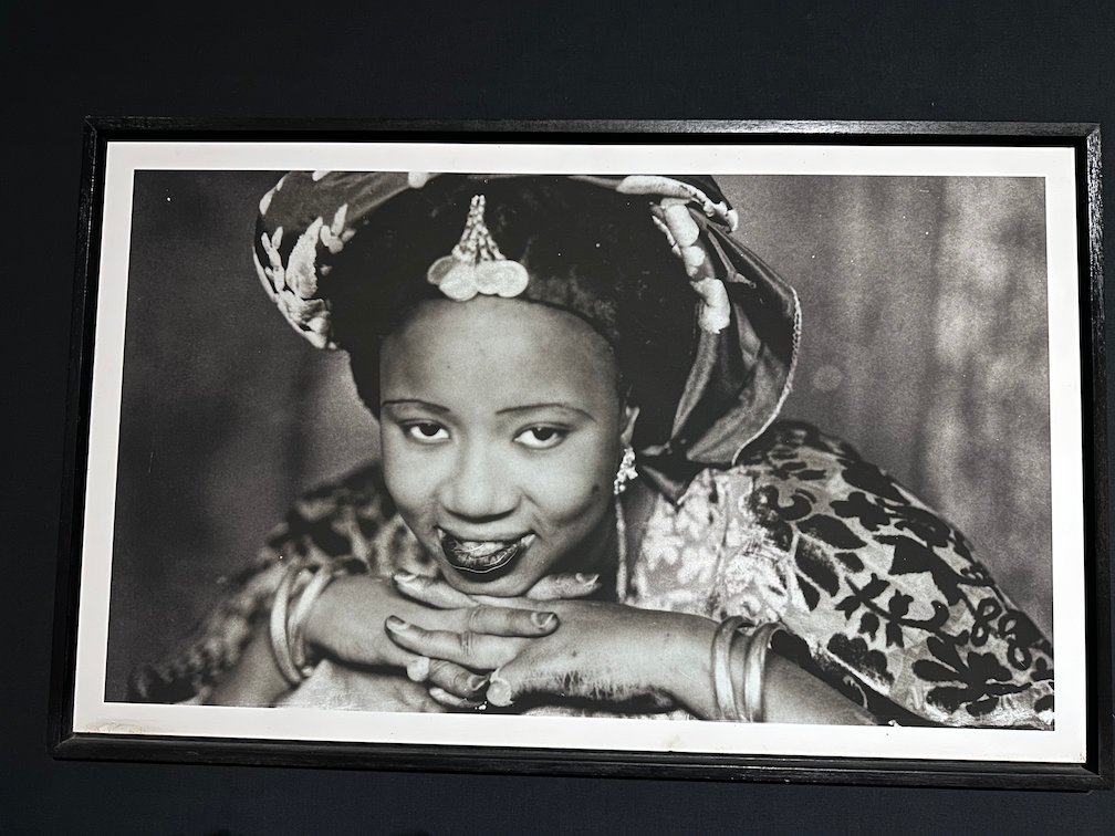 An old black and white portrait shows a smiling woman with jewelry.