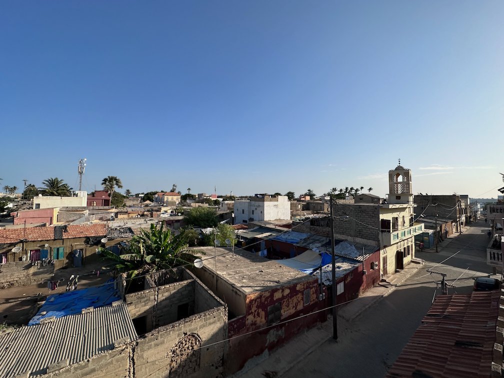 Roofs and a tower stand under a clear sky in Saint-Louis.