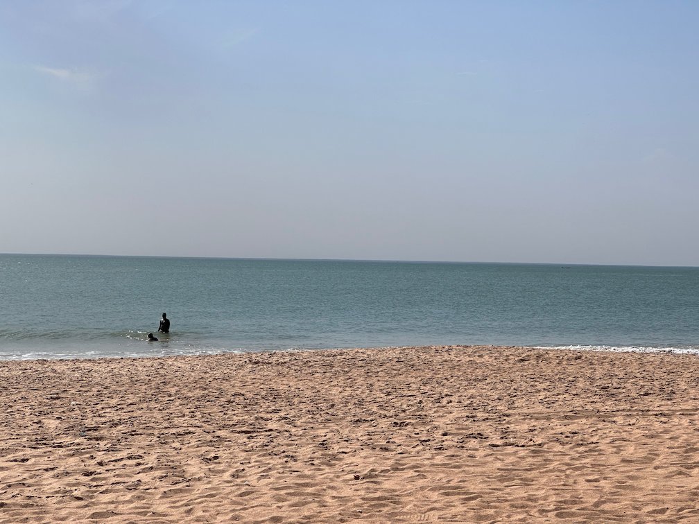 A swimmer is in the calm sea off the sandy beach in Saly.