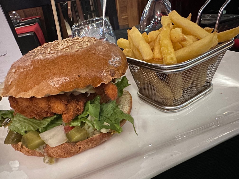 A chicken burger and fries stand on a plate in a restaurant in Saly.