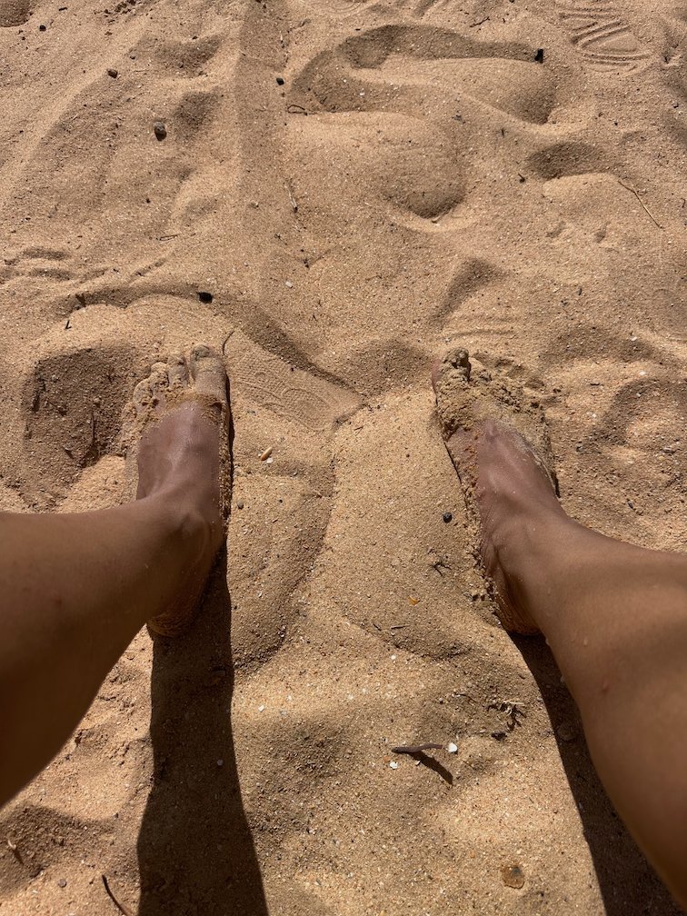 Bare feet rest in the sand in the shade on the beach in Saly.