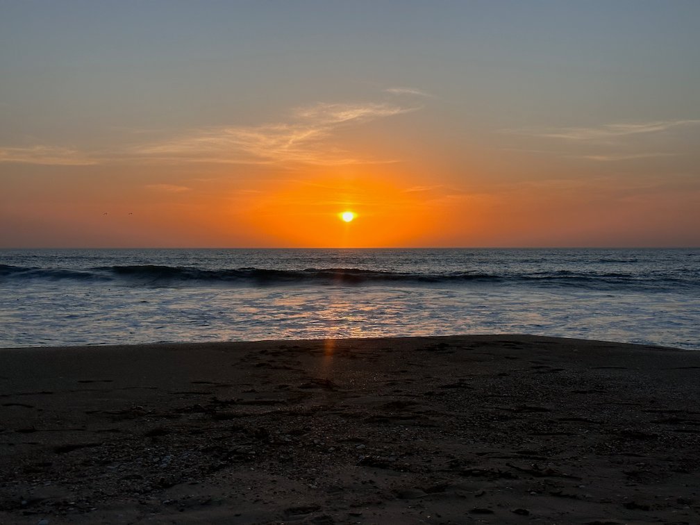 An orange sun sets over the calm sea in Saly.