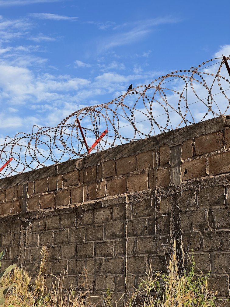 Razor wire runs along the top of a block wall in Saly.