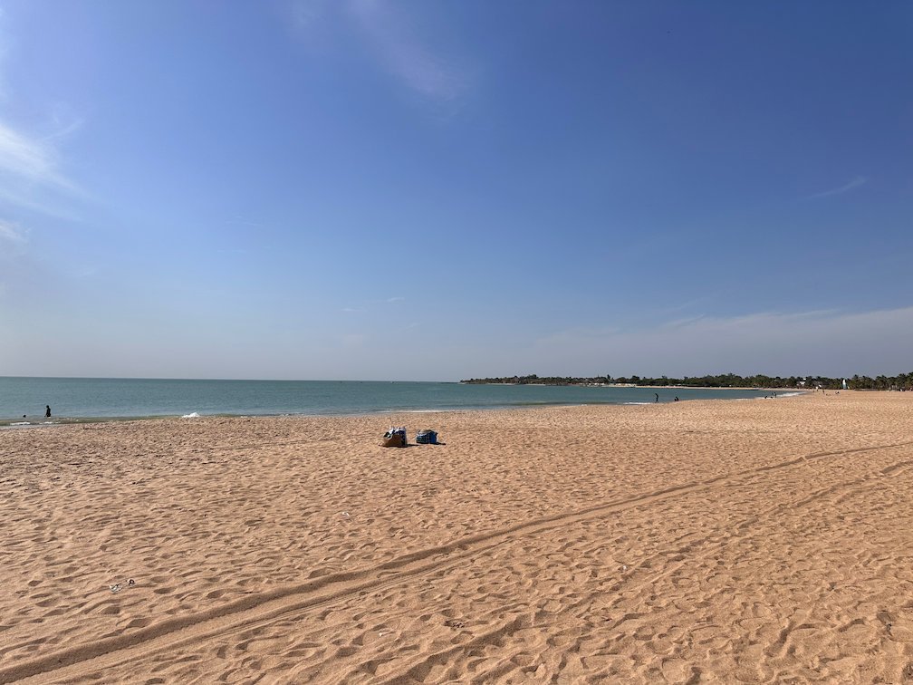 A wide sandy beach runs along the calm sea in Saly.