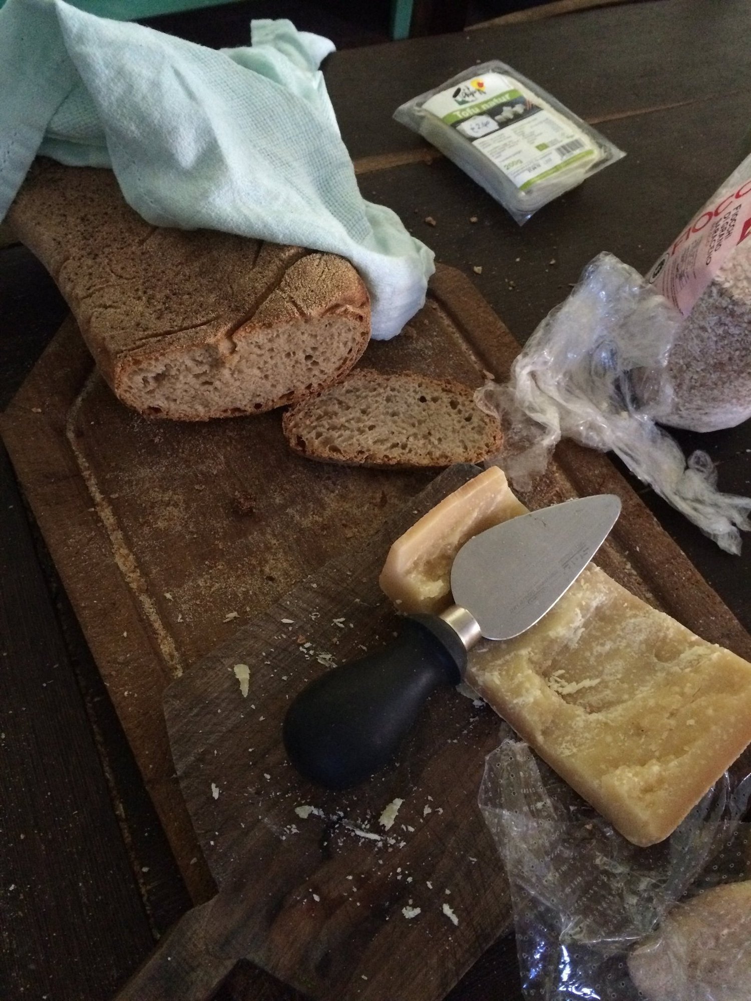 Homemade bread and a piece of hard cheese lie on a wooden board in Sardinia.