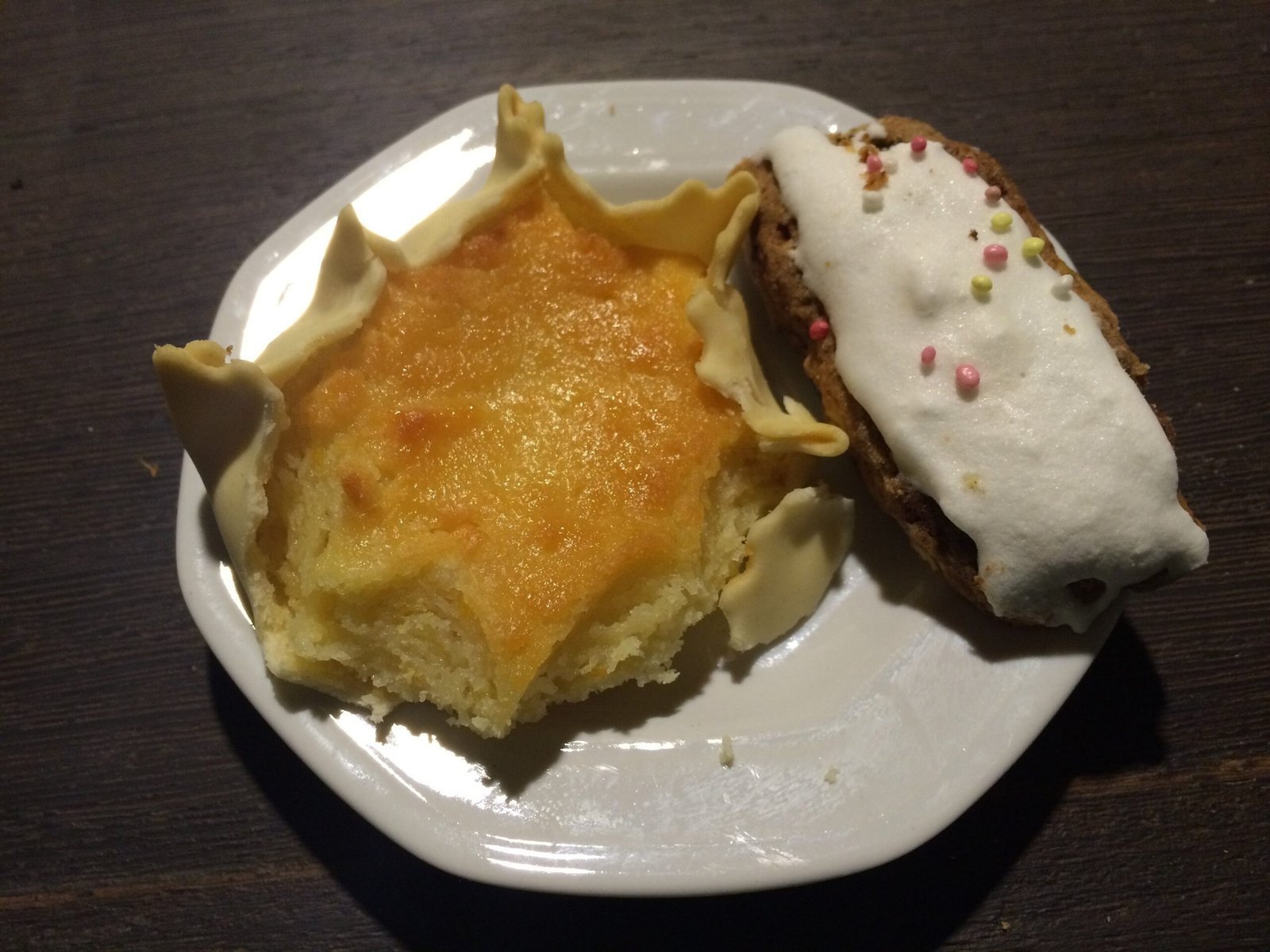 A cheese pastry and a cake with white icing lie on a plate at Easter in Sardinia.