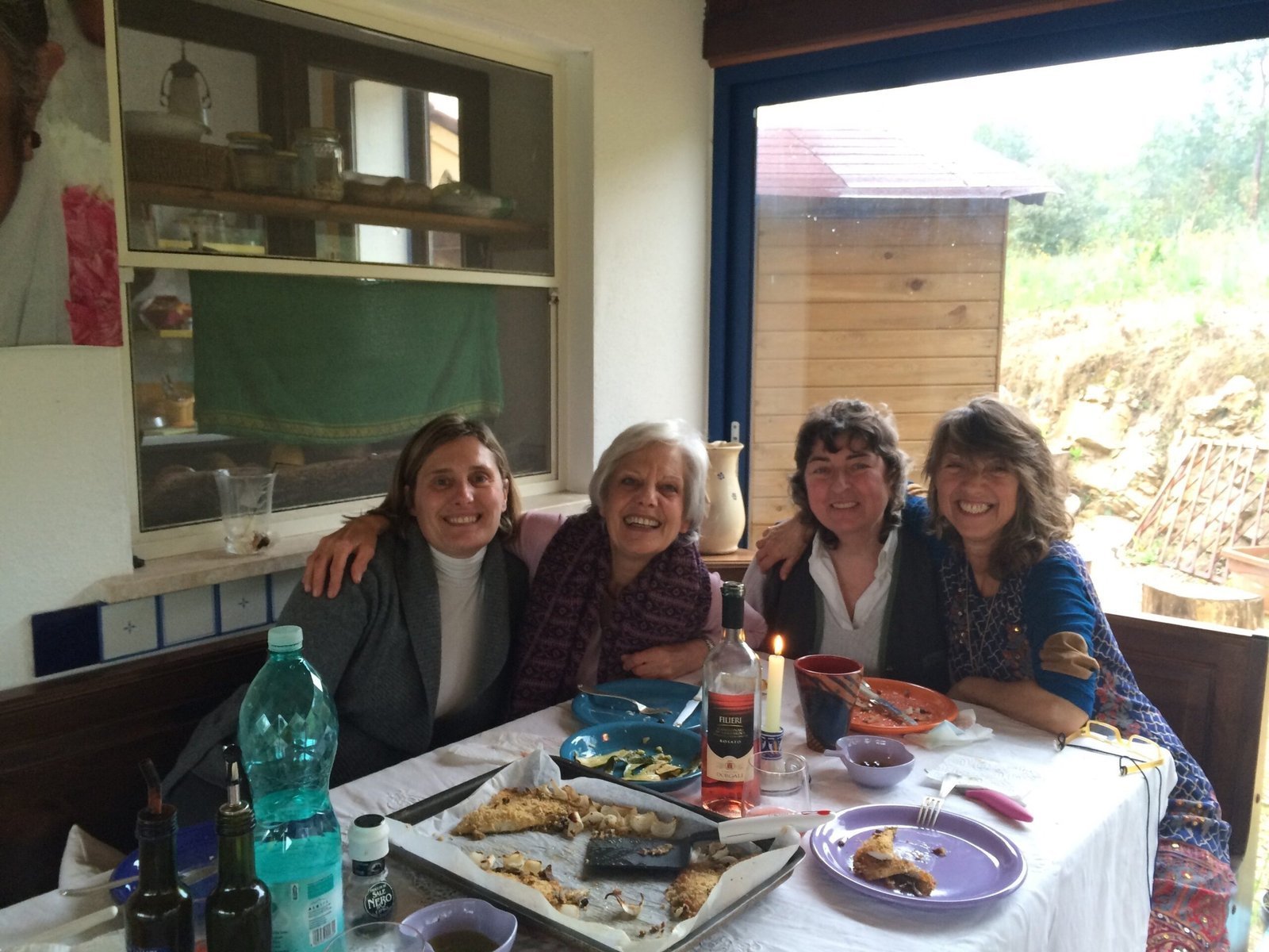 Four women sit together at a dinner table in a farmhouse kitchen in Sardinia.